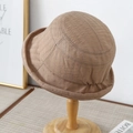 Detail of light brown bucket hat with fine fabric texture and rolled edge on wooden stand - M (56-58cm) / Coffee