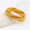 Elegante pulsera elástica de acero inoxidable dorado de cuatro capas sobre podio - Talla única / Dorado