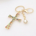Golden metal cross keychain with colorful rhinestones and waterdrop pendant on white background - Colorful