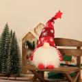 Leuchtendes Weihnachtsgnom-Plüschtier mit roter Schneeflockenmütze auf Holzbank - Rot