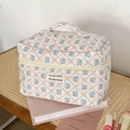 Detailed close-up of quilted floral makeup bag with blue and pink flowers on book desk - Makeup Bag (Large) / Rose Grid