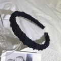 Close-up of black fabric sponge headband with frayed edges on white pleated cloth - Black