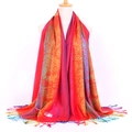 Detail showing the 100% Pashmina fabric label and tassels on a colorful jacquard scarf - Peacock Red