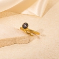 Detailed view of a gold snake ring with black opal inlay on a beige stone texture - Black Stone Snake Style (R0736)