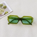 Detail view of stylish green oval sunglasses with translucent frames on white textured background - Dark Emerald