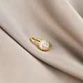 Macro detail of golden clip-on nose ring with clear zircon on beige silk fabric - Single Zircon (E5689-21)