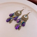 Dettaglio degli orecchini bohémien con nappe a foglia e perle viola su ceramica - Stile Foglia Goccia d'Acqua Viola