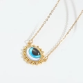 Detailed close-up of golden Devil's Eye pendant with blue oil drip and white zircons - White