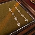 Macro detail of gold-plated geometric long earrings on a luxury green velvet background - Long Hollow Drop Earrings / Ear Hook - Gold