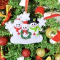 Detailed view of resin snowman family ornament hanging on a Christmas tree branch - 3 People Snowman Family