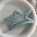 Close-up of a blue star-shaped shark hair claw clip inside a white ceramic bowl - Glossy Blue Star