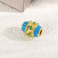 Macro detail of gold oval charm bead with sky blue enamel and emerald green zircon - Sky Blue