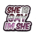 Enamel brooch with SHE IS GAY I'M SHE text and LGBTQ+ pride color stripe pattern - She Is Gay I'm She