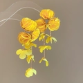 Detail von gelben Chiffon-Blumenohrringen mit goldenen Metallstielen und hängenden Blättern - Gelb
