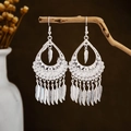 Detailed close-up of Bohemian silver leaf tassel earrings hanging on a natural branch - Silver Hollow Water Drop Feather Tassel Style (E2873-11)