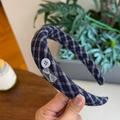 Close-up of blue plaid headband featuring a button detail and 'Hand Made' textile label - Navy Plaid Bow Button Headband