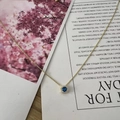 Elegant gold necklace featuring a round blue zircon pendant surrounded by white crystals - December Lake Blue