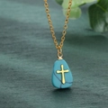 Gros plan détaillé d'une croix dorée sur un pendentif turquoise sur fond en bois sombre - Bleu Turquoise