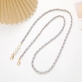 Detalle de cadena de metal con cuero azul claro, perlas blancas y cierres dorados - Azul