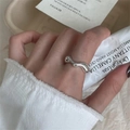 Minimalist wavy silver ring with polished finish worn in a lifestyle aesthetic setting - JZ0211 (Wave Open)