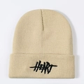 Detail of beige knit beanie showing textured ribbed weave and black HEART embroidery - Beige