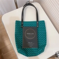 Dettaglio della borsa tote con stampa verde e tracolle in pelle nera su sedia bianca - Catena verde blu