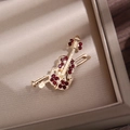 Macro shot of gold violin brooch with red rhinestones in a luxury display case - Gold Red