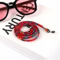 Detail of red bohemian braided eyewear cord with metal tubes and non-slip silicone loops - US 9