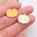 Handheld view of orange enamel pumpkin charm for DIY jewelry with gold metal back - Pumpkin