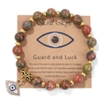 Detail of natural stone bead bracelet featuring a golden Evil Eye charm and rhinestone accents - 19cm / Unakite
