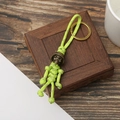 Macro detail of paracord keychain with bronze skull bead and golden ring on wooden base - Fluorescent Green