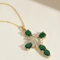 Macro shot of gold cross necklace with green drop gemstones and sparkling zircon detail - Green
