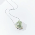 Detail view of large raw light green natural crystal pendant on silver necklace - Prehnite