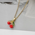 Gros plan d'un collier pendentif cerise dorée avec fruits rouges et feuilles en émail vert - Collier Pendentif Cerise