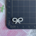 Close-up of white ABS pearl bow charm on a measuring mat showing 1.8cm width size - Bow