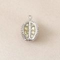 Macro view of silver durian charm with yellow crystals on beige fabric texture background - Silver (Durian)