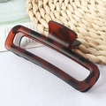 Square dark brown tortoiseshell hair claw clip in glossy finish on a woven mat - Red Tortoiseshell