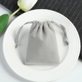Close-up of a grey velvet drawstring jewelry pouch on a white plate with tulips - Gray