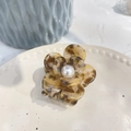 Detail of a brown tortoiseshell floral hair claw clip featuring a pearl center on a ceramic plate - 5.3cm / Yellow Coffee Texture