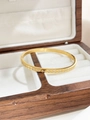 Details des goldfarbenen Titanstahl-Armreifs mit Rautenmuster in einer edlen Holzbox - Raute