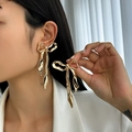 Detail of oversized gold metallic bow earrings with irregular wrinkled texture on a model - 3D Bow Knot (3492) / Gold (3492)