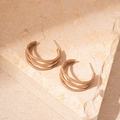 Detailaufnahme khakifarbener mehrlagiger C-förmiger Spiralohrringe auf strukturiertem Stein - C-förmiger Spiralstil / Hellkaffee