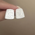 Close-up of geometric resin stud earrings with silver borders and marble texture - Silver-White