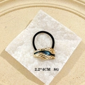 Detail of golden geometric hair ring with teal enamel on a white textured stone background - Black Enamel Style