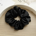 Classic black satin scrunchie with a silk-like finish and soft pleats in a rustic setting - L Black
