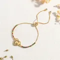 Detail of gold heart bracelet featuring colorful zircon alphabet inlay and adjustable chain - Letter G