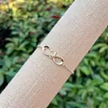 18K gold plated infinity bracelet featuring clear zircon stones on a linen display stand - Micro-pave Infinity