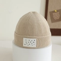 Close-up of beige ribbed knit beanie with vertical stripes and white lettered leather patch - 1-4 Years / Beige