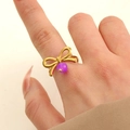 Anello a fiocco in acciaio dorato con perla viola, mostrato indossato da una modella - Anello con fiocco viola placcato oro 18K (11438)