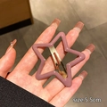 Detalle de una pinza para el pelo estrella rosa-púrpura de 5,5cm sostenida por una mano - Púrpura Brumoso